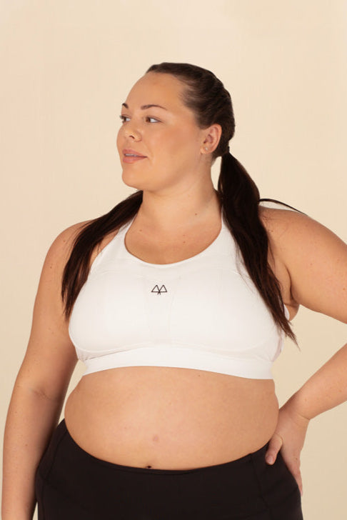 Woman in White Sports Bra size 38E with hand on her hip