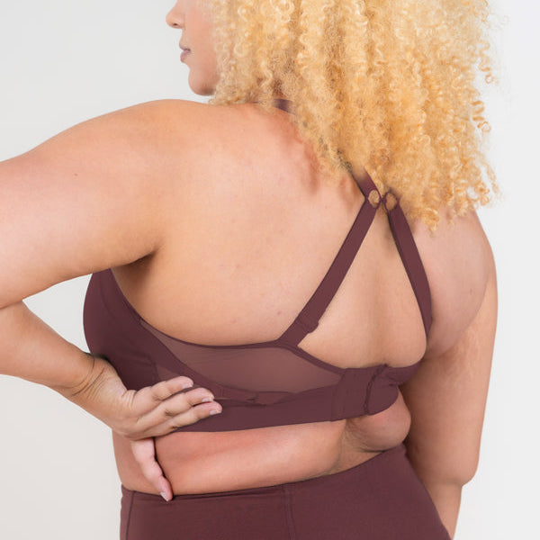 Woman wearing a maroon sports bra and leggings on a white background
