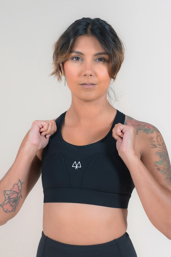 Woman wearing a Black Sports Bra with her hands on the straps.