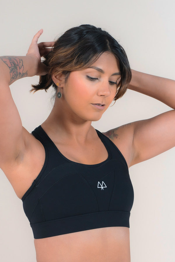 Athlete standing with her arms above her head, playing with her hair, while wearing a MAAREE sports bra