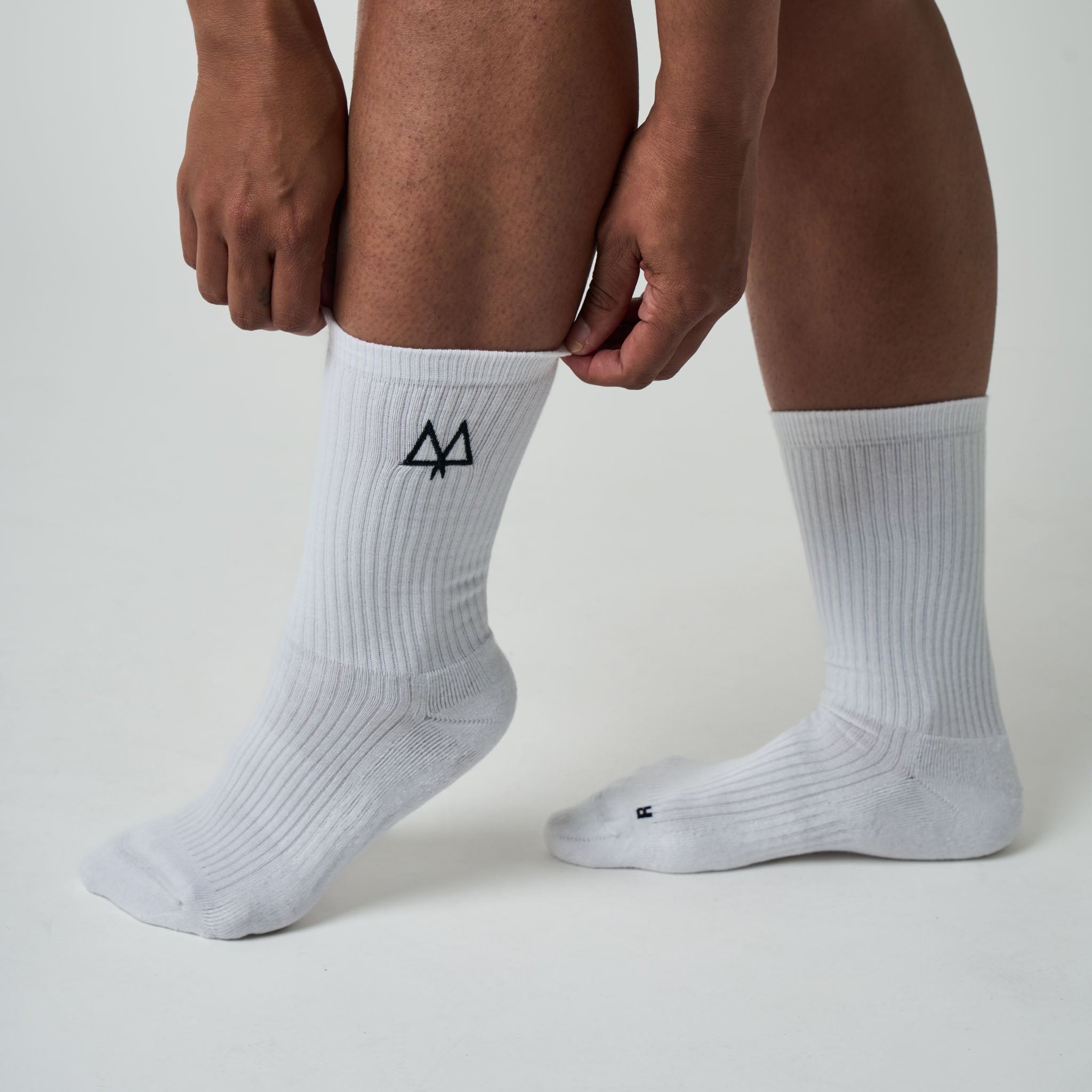 White socks with a black logo worn by a person on a light gray background