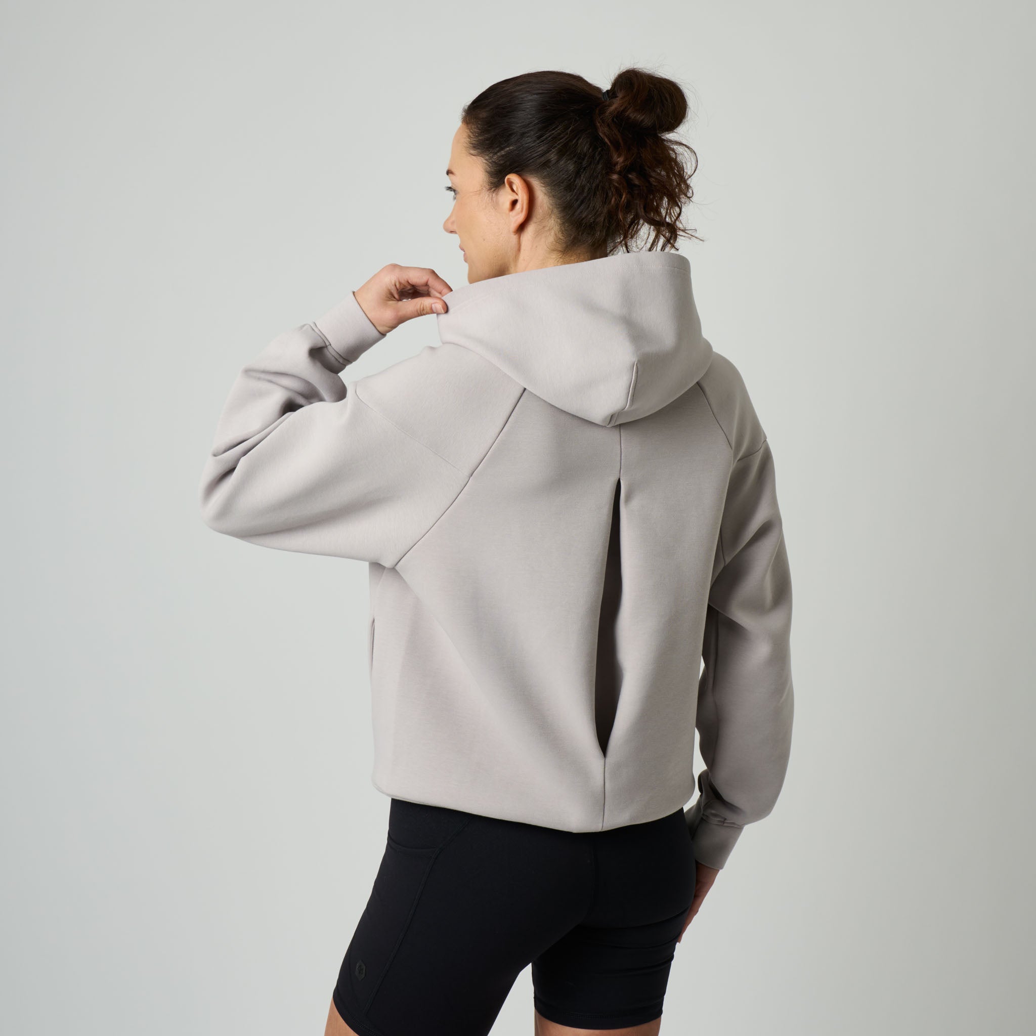 Person wearing a light gray hoodie and black shorts on a plain background