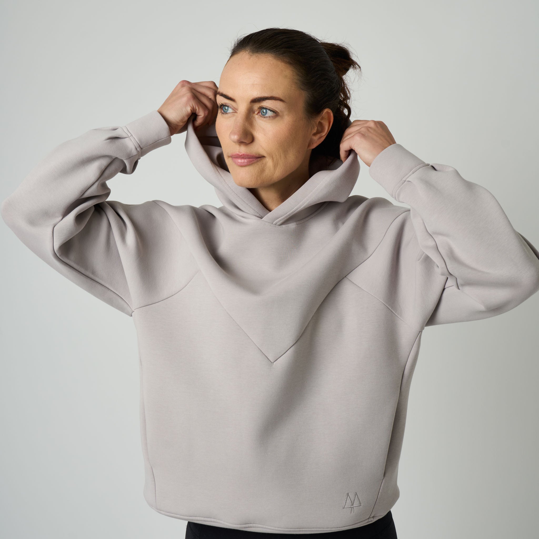 Woman wearing a light gray hoodie against a plain background