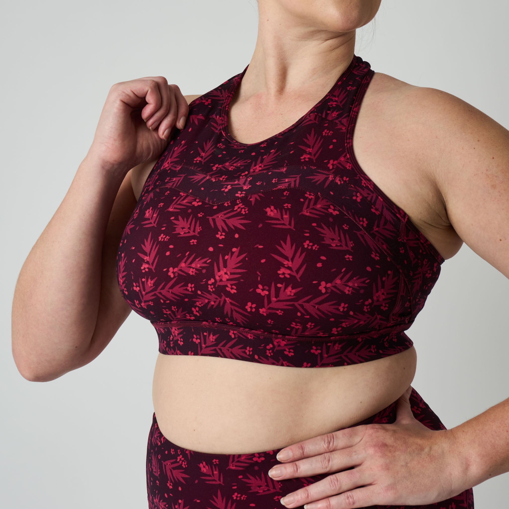 Person wearing a red and black patterned sports bra and leggings on a plain background